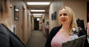 Two people talking in a hallway, one of them holding a clipboard